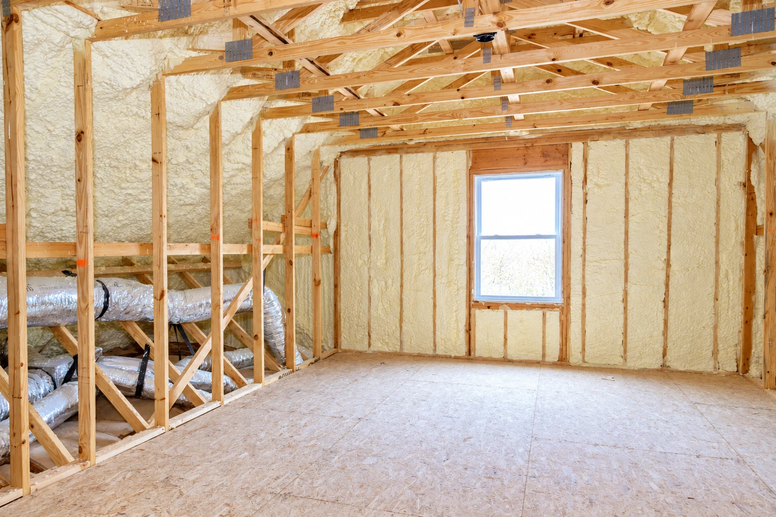 Unfinished room with exposed wooden framing and pale spray foam filling the wall cavities.